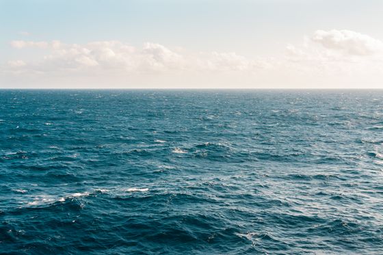 Open sea beneath a pale, clouded sky